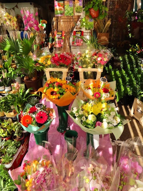 A vibrant display of freshly arranged floral bouquets at a flower shop, featuring a variety of flowers including bright red, yellow, pink, and white blooms, wrapped in colorful paper and placed in gre